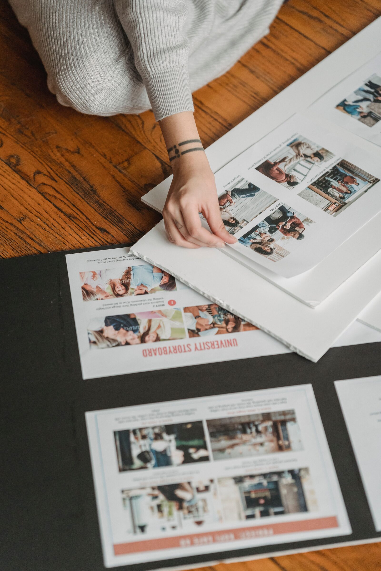 A hand arranges printed storyboard layouts across a table.